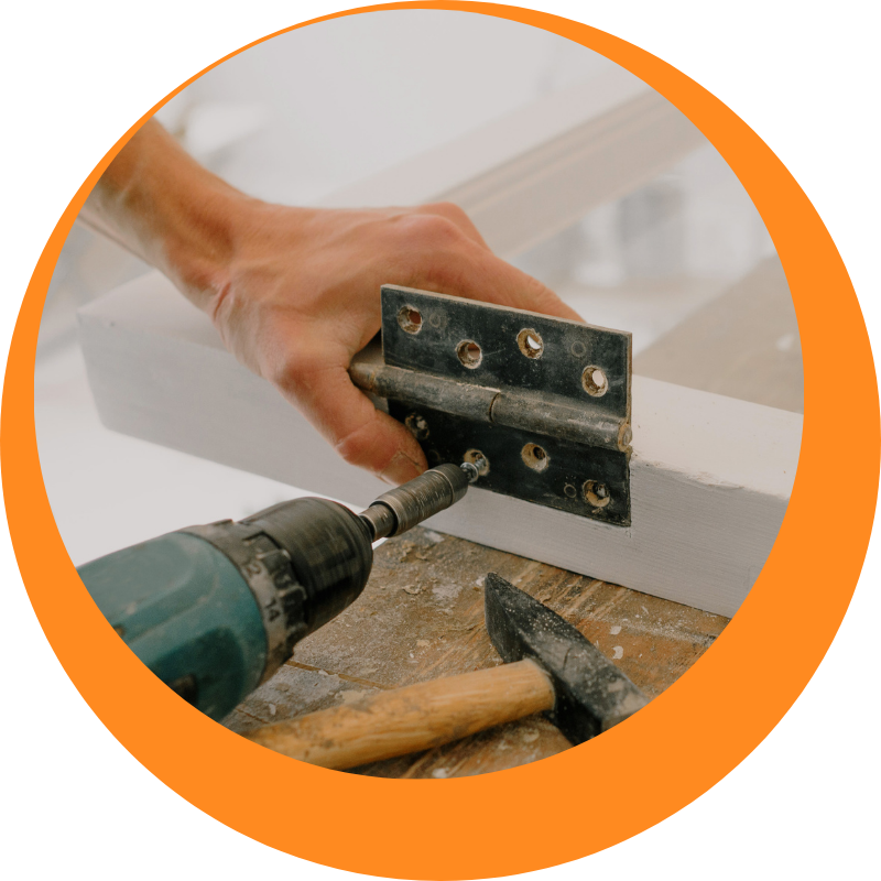 A handyman in Chippendale installing a metal hinge on a wooden frame with a power drill, showcasing professional home improvement and repair skills.